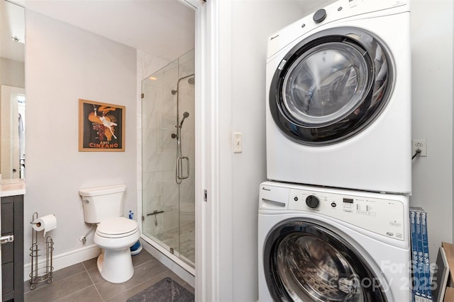 full bath with tile patterned flooring, a shower stall, stacked washing maching and dryer, baseboards, and toilet