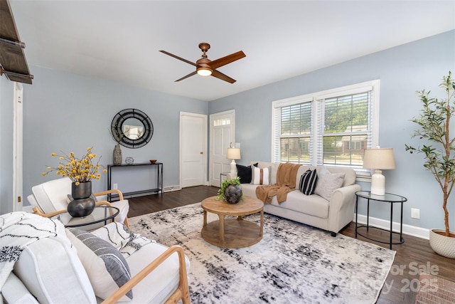 living room featuring baseboards, a ceiling fan, and dark wood-style floors