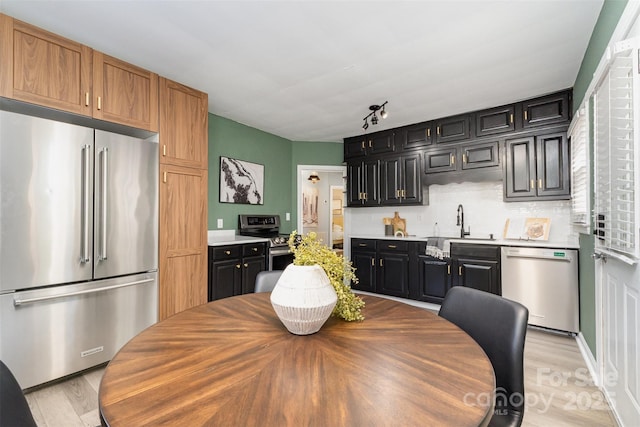kitchen with a sink, light countertops, dark cabinetry, and stainless steel appliances