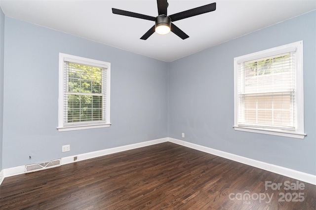 spare room with a ceiling fan, baseboards, dark wood finished floors, and visible vents