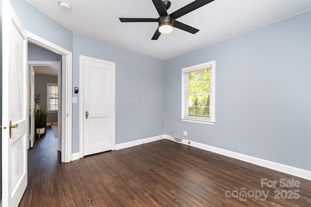 unfurnished bedroom with baseboards, multiple windows, dark wood finished floors, and visible vents