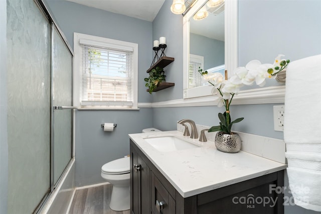 full bathroom with vanity, enclosed tub / shower combo, wood finished floors, and toilet