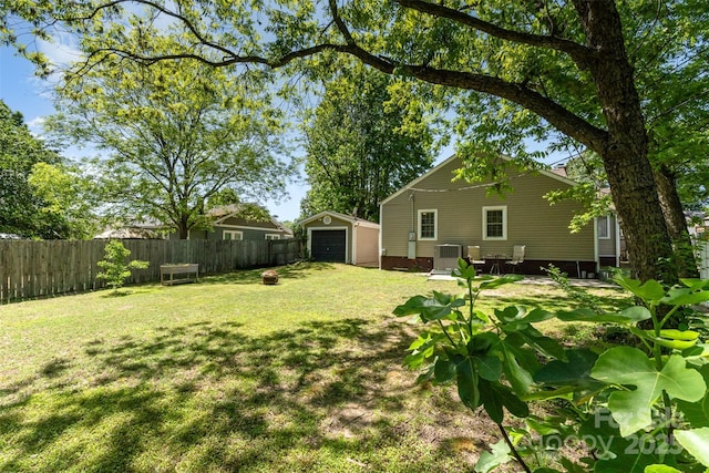view of yard featuring an outdoor structure, a fenced backyard, central air condition unit, and a detached garage