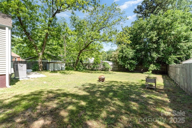 view of yard featuring an outdoor structure, a fenced backyard, and a storage shed