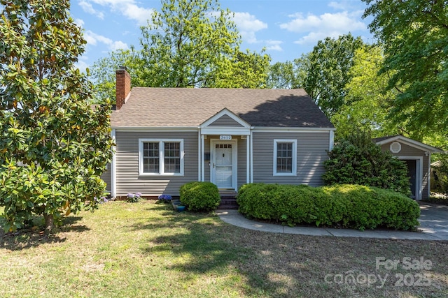 view of front of home with roof with shingles, a chimney, and a front yard