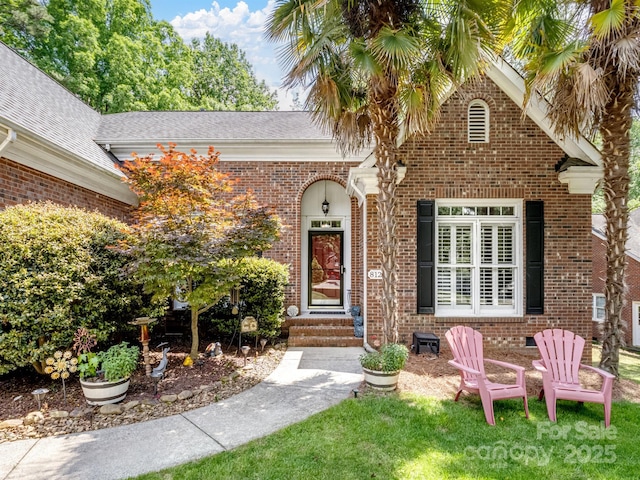 view of exterior entry with a yard and brick siding