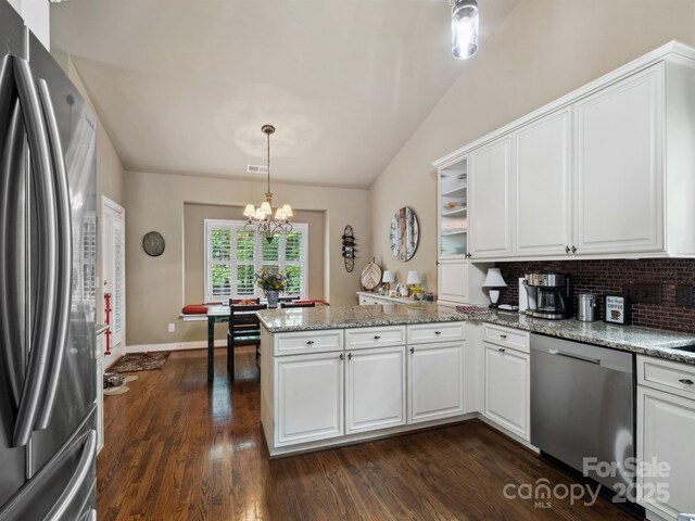 kitchen featuring a peninsula, lofted ceiling, dark wood-style floors, a notable chandelier, and stainless steel appliances