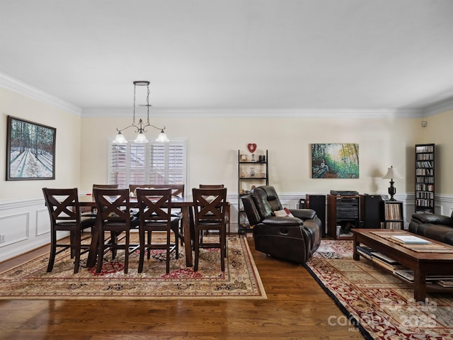 dining area featuring crown molding, wainscoting, wood finished floors, and a chandelier