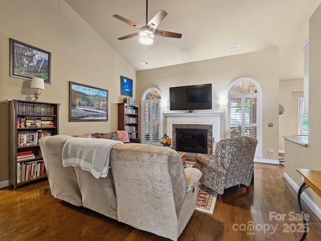 living room with visible vents, a brick fireplace, wood finished floors, baseboards, and ceiling fan