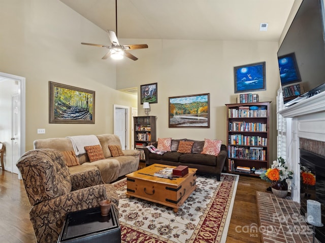 living area featuring a brick fireplace, a ceiling fan, high vaulted ceiling, and wood finished floors