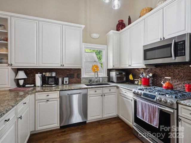 kitchen featuring a sink, tasteful backsplash, stainless steel appliances, and white cabinetry