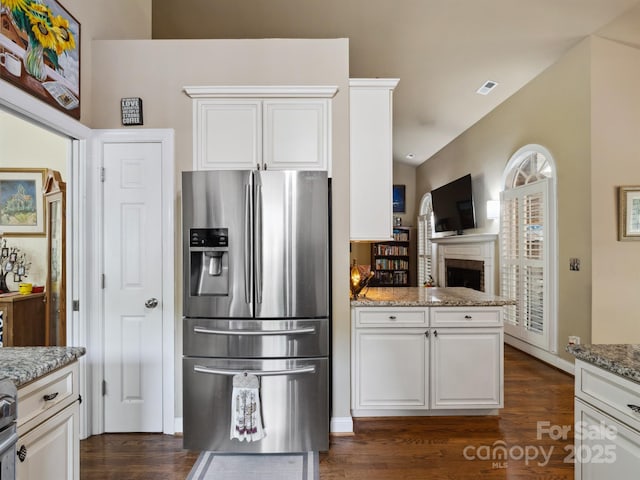 kitchen with dark wood finished floors, white cabinets, light stone countertops, and stainless steel refrigerator with ice dispenser