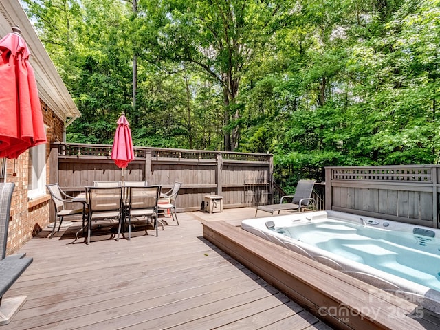 deck featuring hot tub deck surround and outdoor dining space