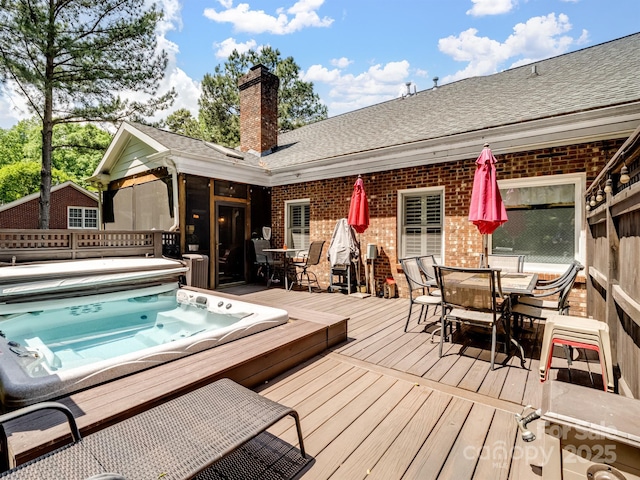 exterior space with brick siding, hot tub deck surround, outdoor dining area, and a deck