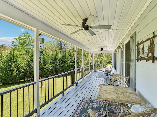 wooden terrace with a ceiling fan, covered porch, and a yard