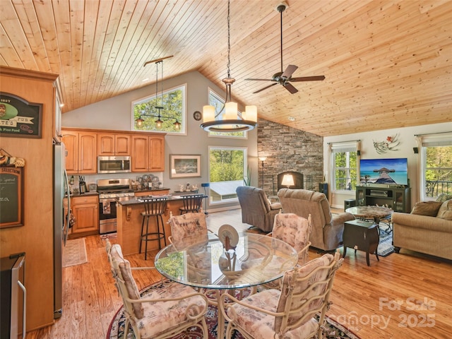 dining room with light wood-style floors, a fireplace, high vaulted ceiling, a ceiling fan, and wood ceiling