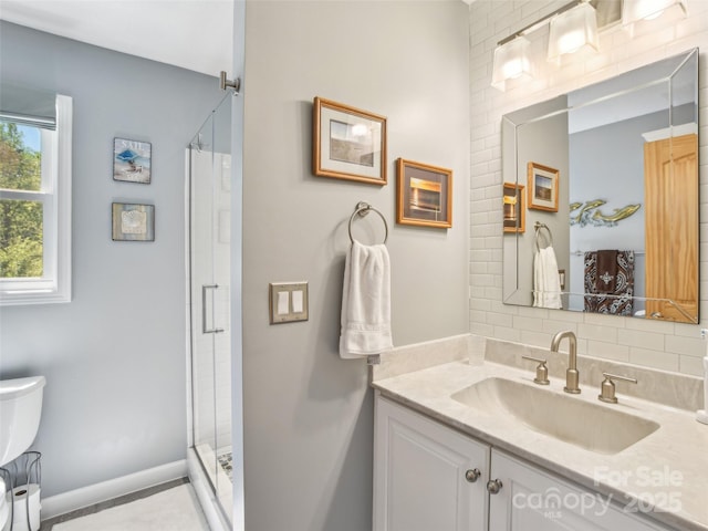 full bathroom with vanity, toilet, baseboards, and a stall shower