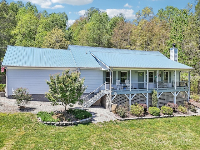ranch-style house featuring a front lawn, covered porch, a chimney, and metal roof