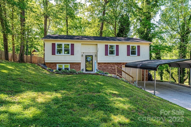 bi-level home featuring a front yard, a detached carport, brick siding, fence, and concrete driveway