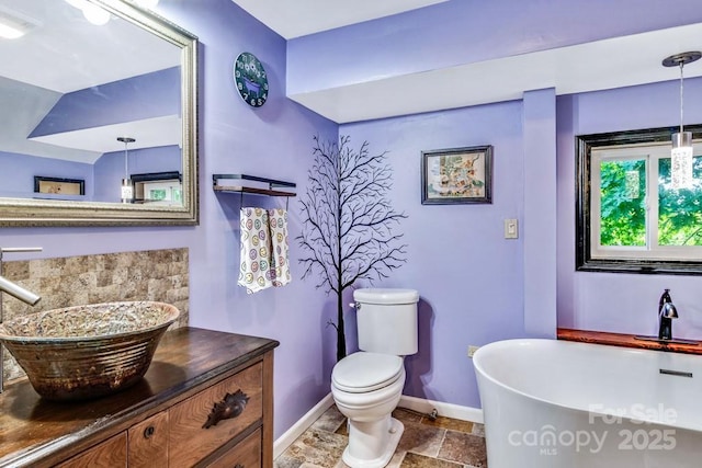 76 Archer Rd, Saluda, NC 28773 - bathroom featuring baseboards, a freestanding bath, stone tile flooring, toilet, and vanity