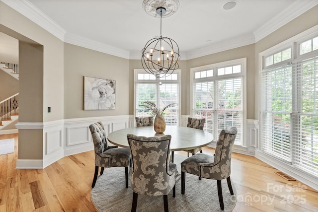 dining area with stairway, wainscoting, light wood finished floors, and a chandelier