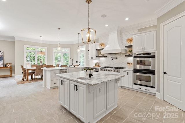 kitchen with stainless steel double oven, a center island with sink, a sink, custom exhaust hood, and a peninsula