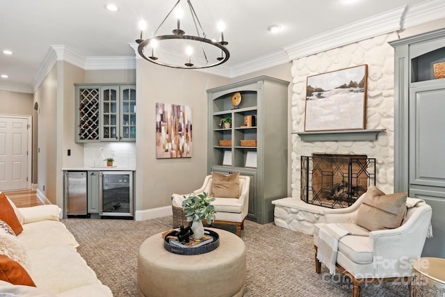 living room with crown molding, a fireplace, a chandelier, wine cooler, and a bar