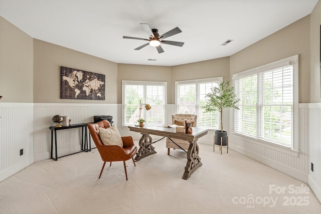 office space with visible vents, ceiling fan, a wainscoted wall, and carpet floors