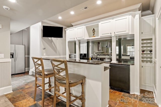 kitchen featuring white cabinets, a breakfast bar, black dishwasher, stone tile floors, and stainless steel refrigerator with ice dispenser