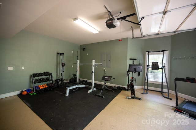 workout area featuring a garage, baseboards, and electric panel