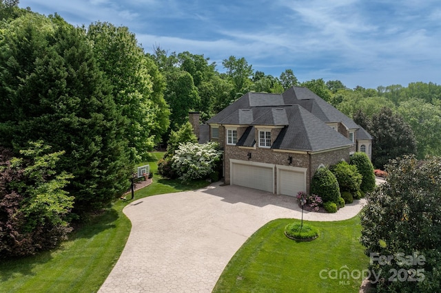 view of front of house with brick siding, a garage, a front lawn, and driveway