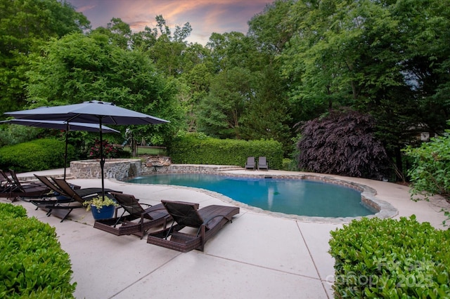 pool at dusk featuring a patio area and an outdoor pool
