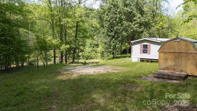view of yard with an outdoor structure, a storage unit, and a forest view