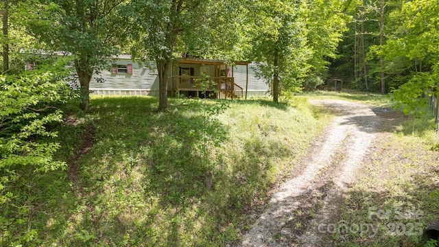 exterior space with dirt driveway and a view of trees