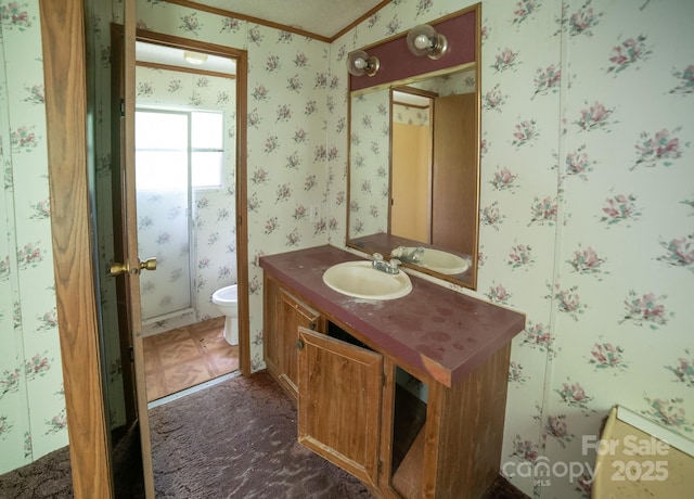 half bathroom featuring vanity, ornamental molding, toilet, and wallpapered walls