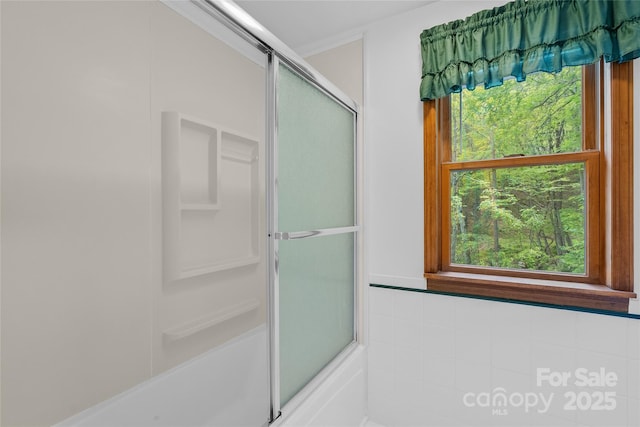 bathroom featuring a wealth of natural light and bath / shower combo with glass door