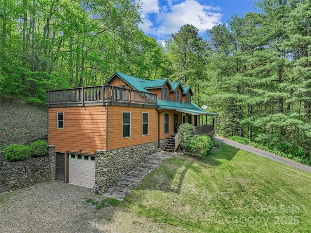 view of front facade with a front yard, gravel driveway, an attached garage, stairs, and stone siding