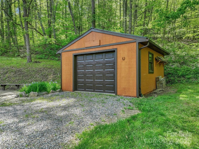 detached garage featuring driveway and a wooded view