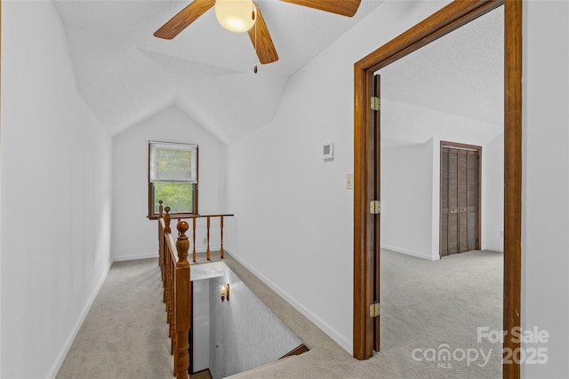 hallway with baseboards, carpet flooring, lofted ceiling, and an upstairs landing