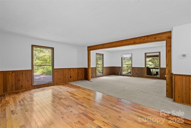 unfurnished living room with wooden walls and a wainscoted wall