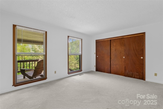 unfurnished bedroom with a closet, carpet flooring, a textured ceiling, and baseboards