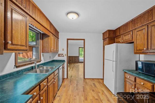 kitchen featuring black microwave, a sink, light wood-style floors, brown cabinetry, and stainless steel dishwasher