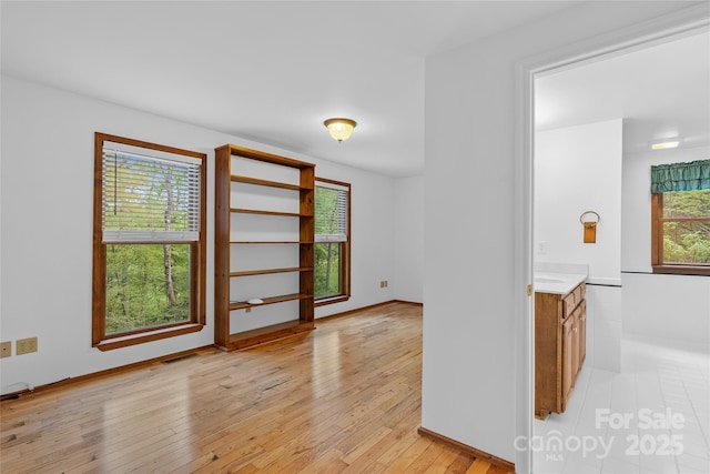 empty room with light wood-style floors and visible vents