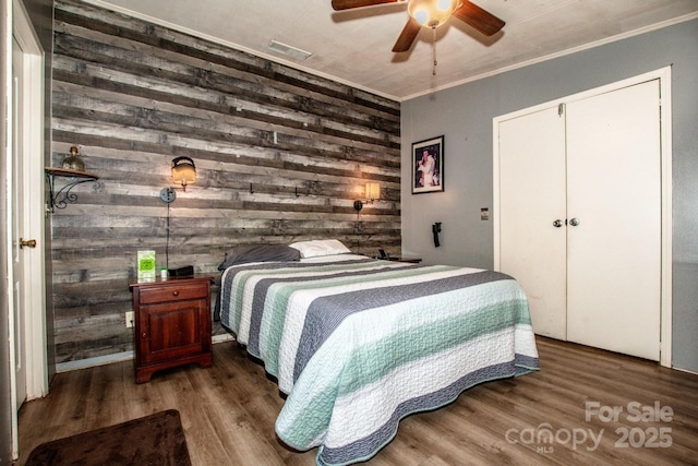 7733 Skyline Dr, Sherrills Ford, NC 28673 - bedroom featuring wooden walls, wood finished floors, ornamental molding, a ceiling fan, and a closet