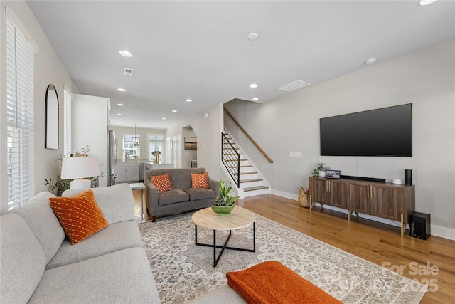 living area with baseboards, visible vents, wood finished floors, and stairway