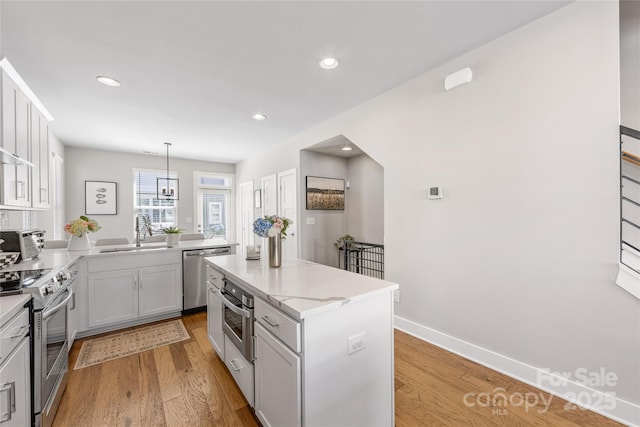 kitchen featuring a center island, light wood-type flooring, a sink, a toaster, and stainless steel appliances