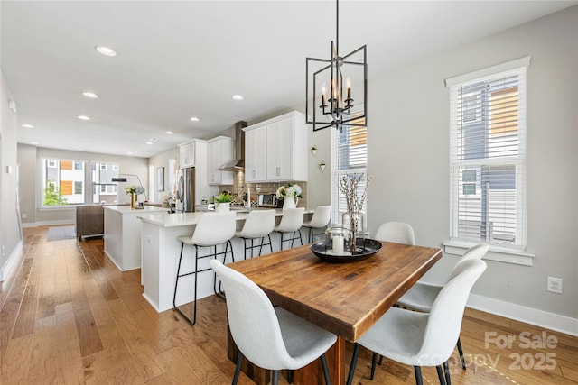 dining area featuring baseboards, an inviting chandelier, and light wood-style flooring