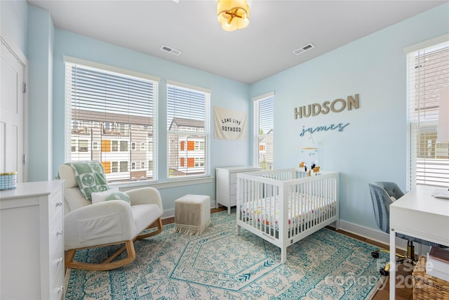 bedroom with baseboards, visible vents, and multiple windows