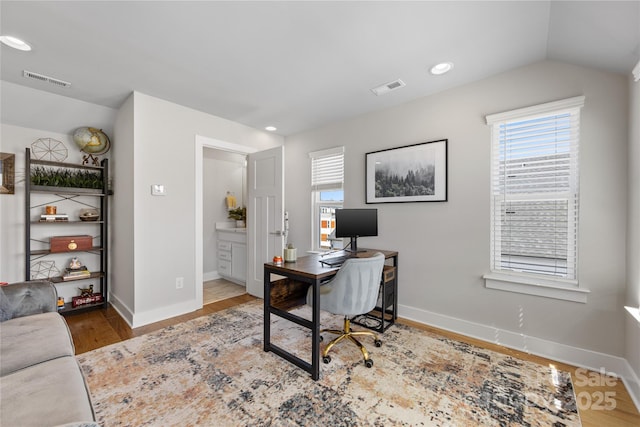 home office featuring baseboards, visible vents, a healthy amount of sunlight, and wood finished floors