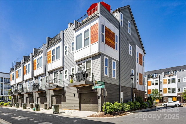 view of property featuring a residential view, an attached garage, and central AC